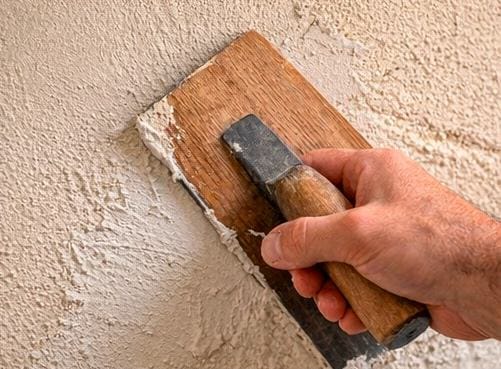 Main de l’artisan Commedelapierre travaillant l’enduit