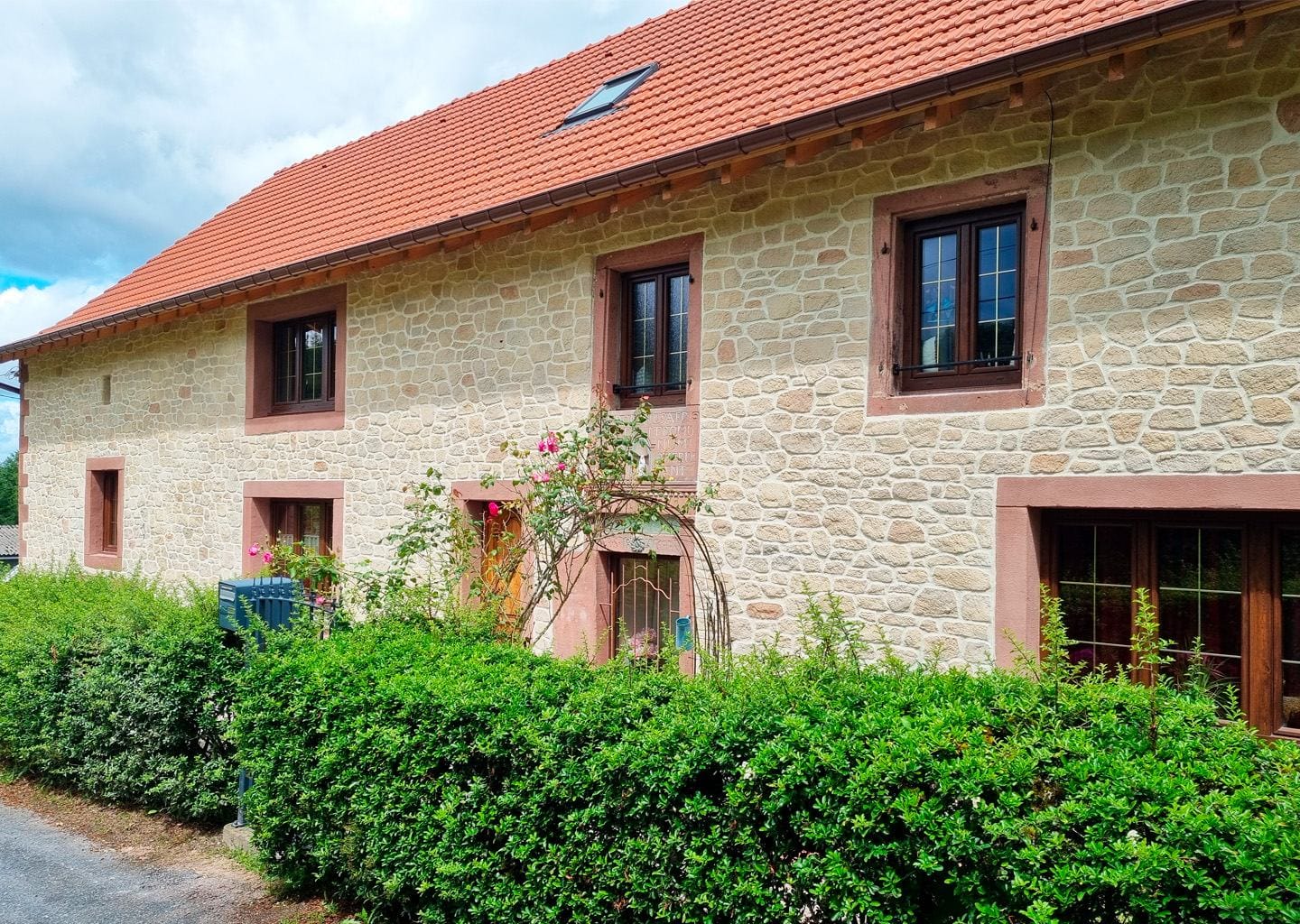 Maison avec façade en imitation pierre apparente et pierres d’angle en grès rouge