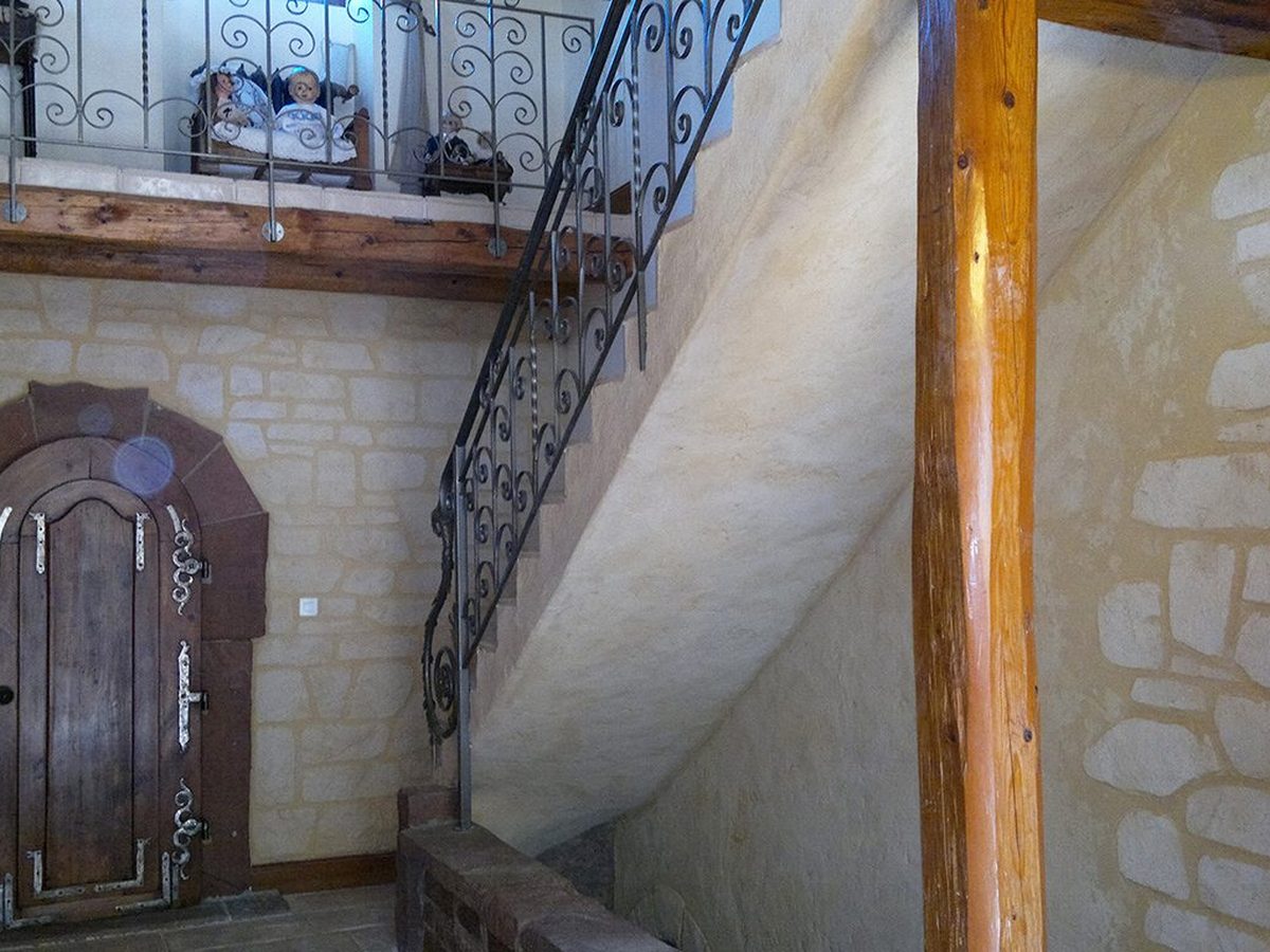 Cage d’escalier en enduit à la chaux et imitation pierre, avec son ancienne porte en bois