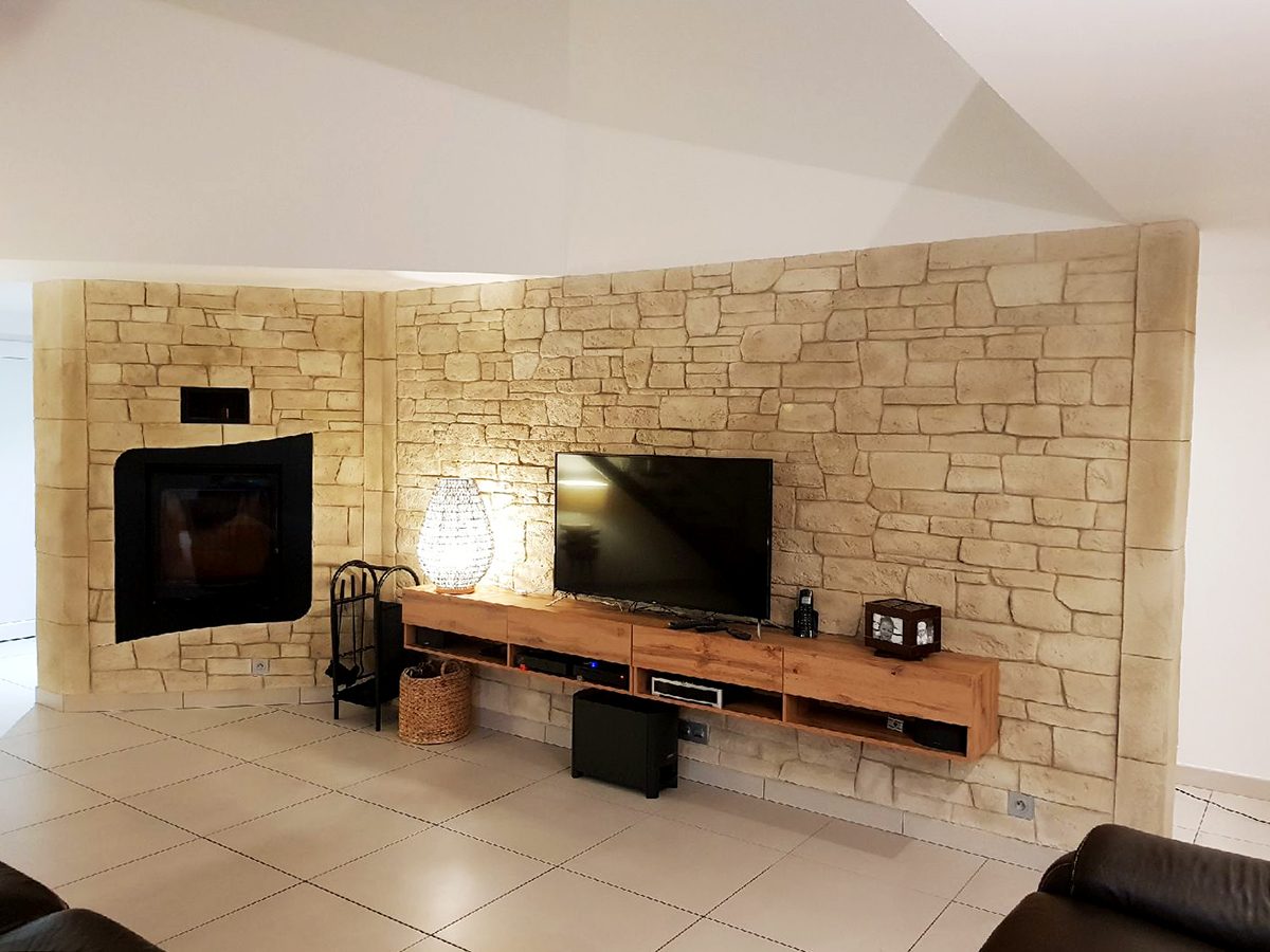 Mur de salon en imitation pierre sèche autour de la cheminée et du meuble télé
