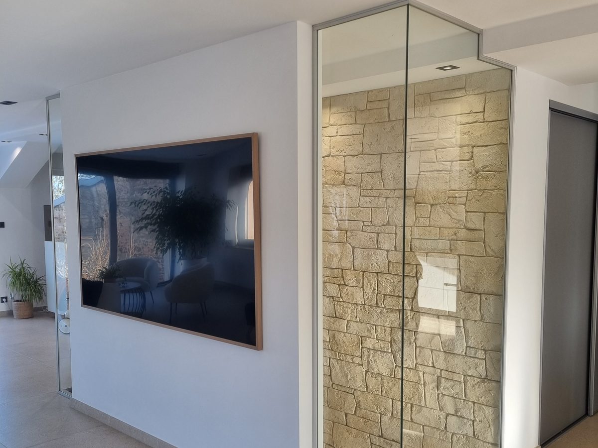 Mur en imitation pierre derrière une paroi vitrée, dans une entrée