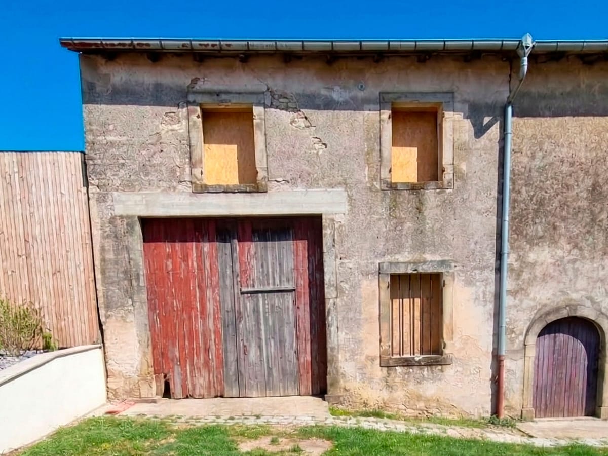 Façade abîmée avec ancienne porte de grange avant rénovation