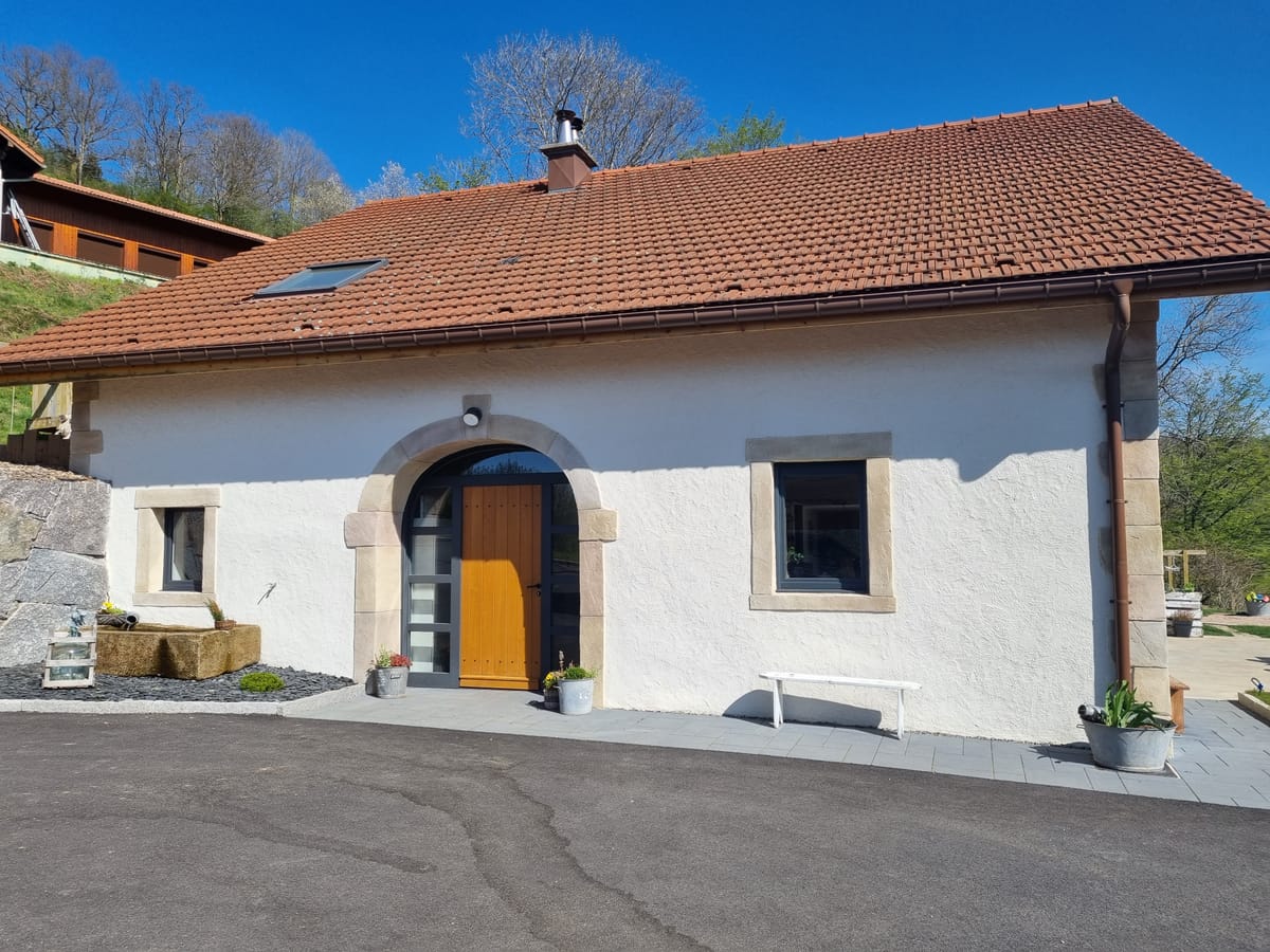 Maison rénovée avec enduit à la chaux clair et porte cintrée en pierre de taille