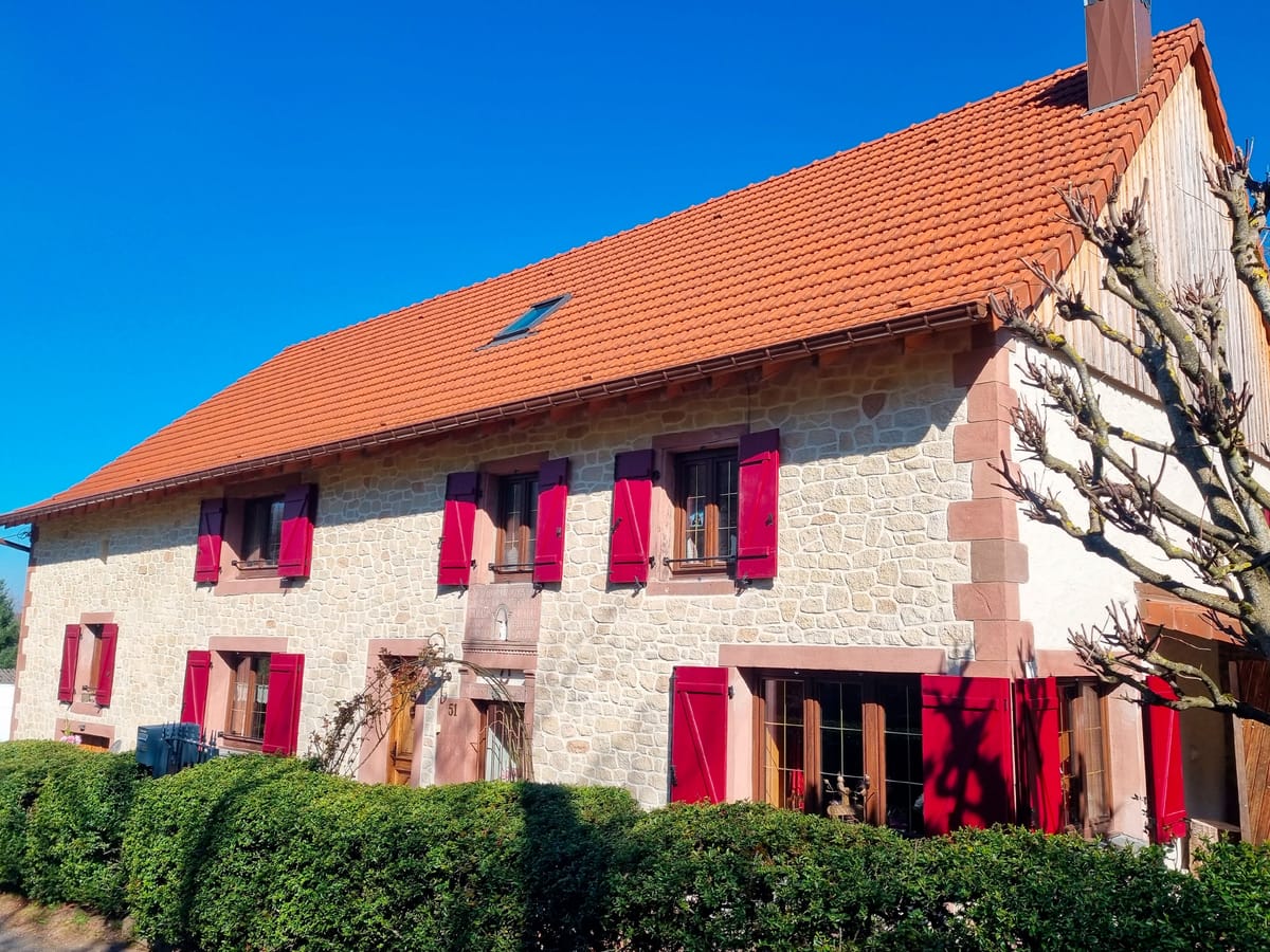 Maison de village en imitation pierre jointée avec volets rouges