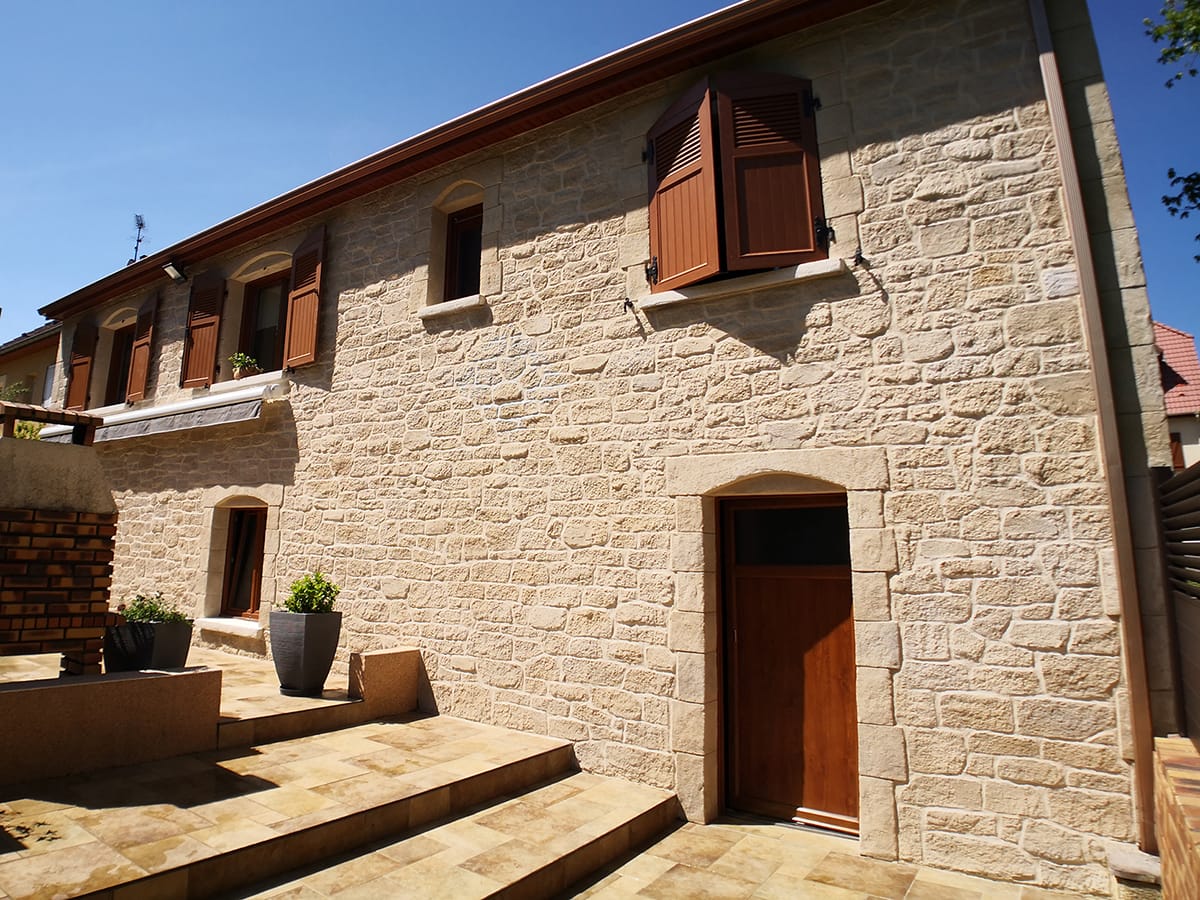 Façade en imitation pierre jointée avec porte cintrée et perron en pierre