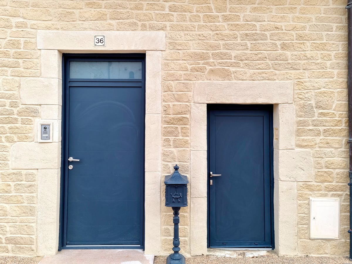 Portes d’entrée bleues avec encadrements en imitation pierre de taille blanche