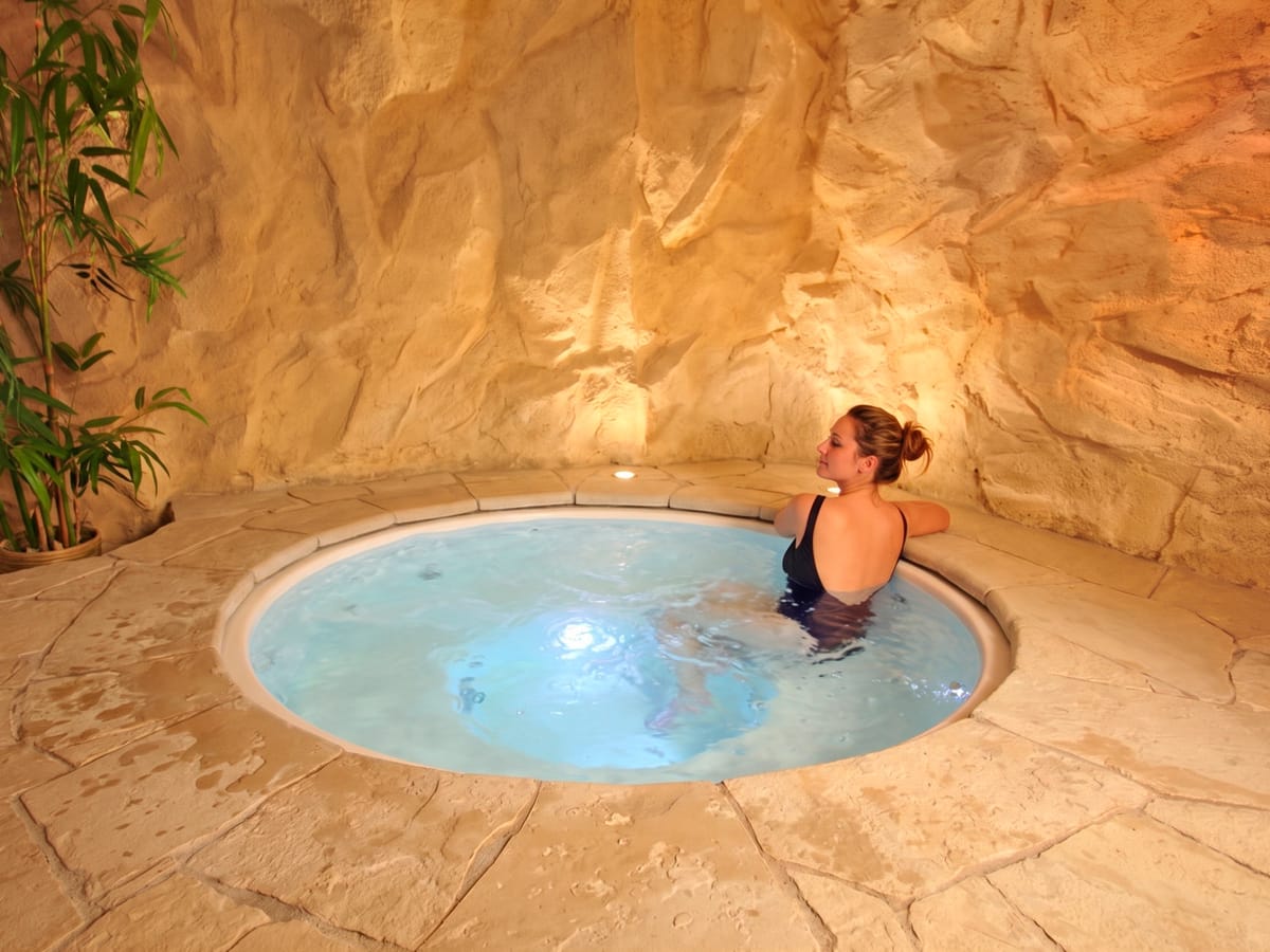 Bain à remous encastré dans un décor en imitation paroi rocheuse et dalles de pierre