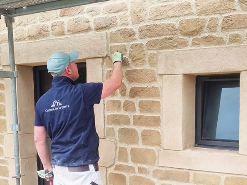 Artisan façadier sculptant une pierre de taille à la main dans les Vosges - Commedelapierre